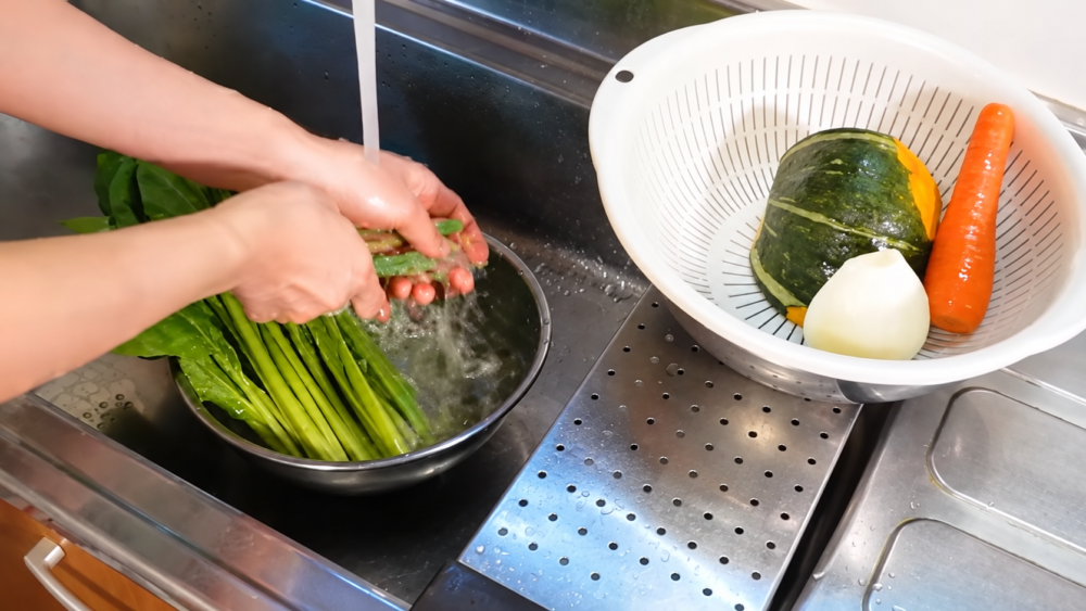 流水で小松菜を洗い、かぼちゃや人参などの野菜を準備する様子